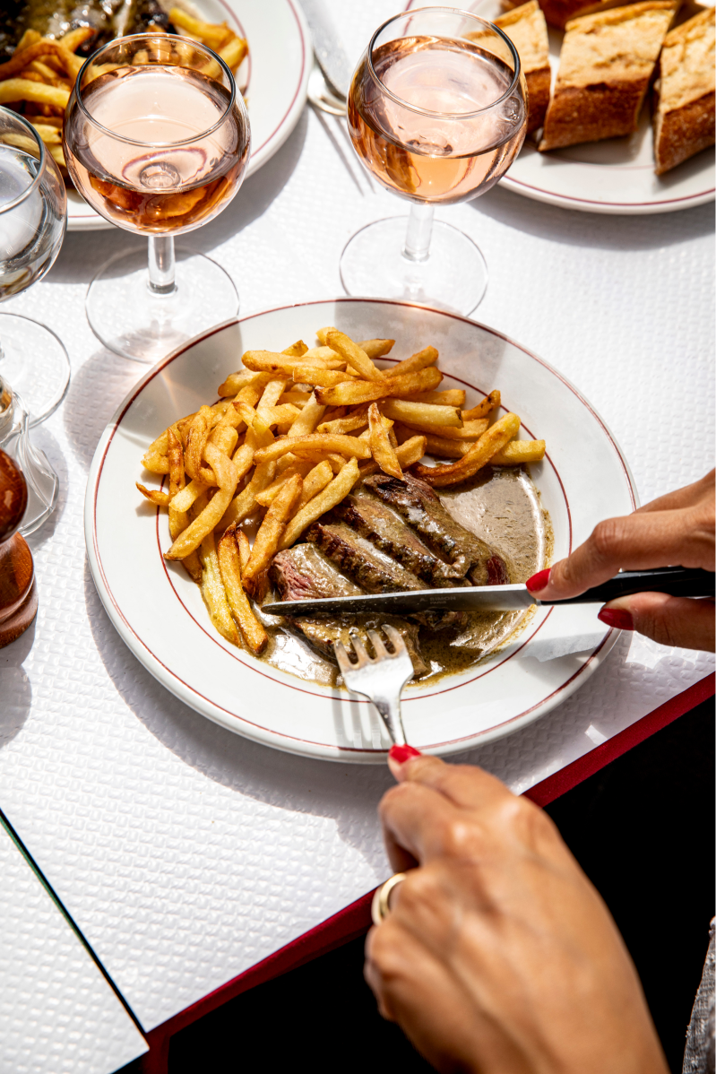 assiette servie en train de couper la viande par une femme aux ongles rouges