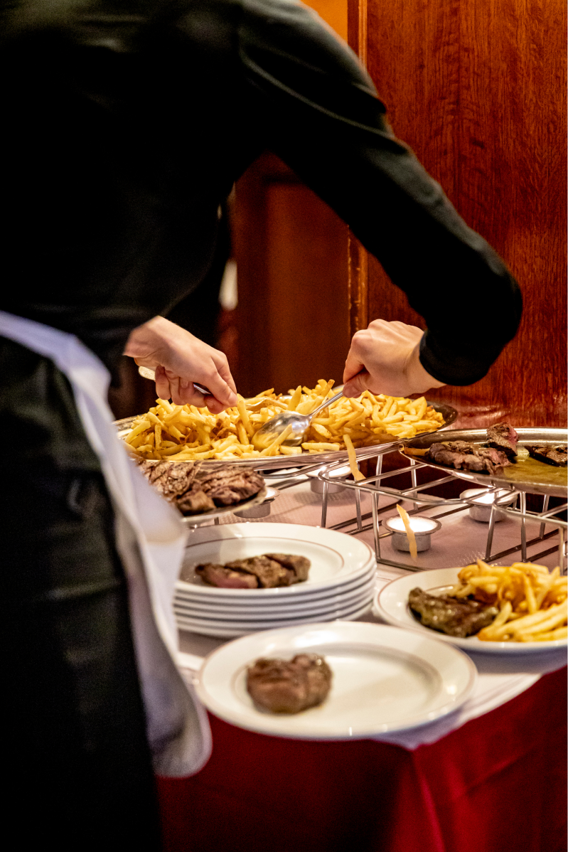 serveuse en train de servir des frites depuis le chauffe plat
